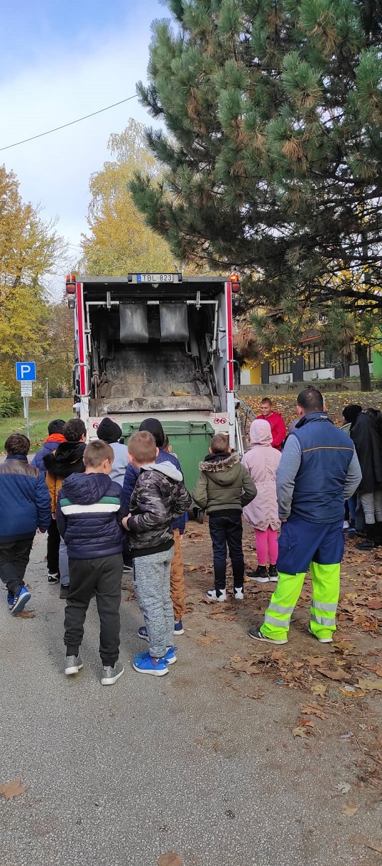 A Társaság dolgozója, Marosán Csaba rakodó mutatja be a gyerekeknek a lakótelepi, 1100 literes hulladéktároló edény ürítését a kukásautón