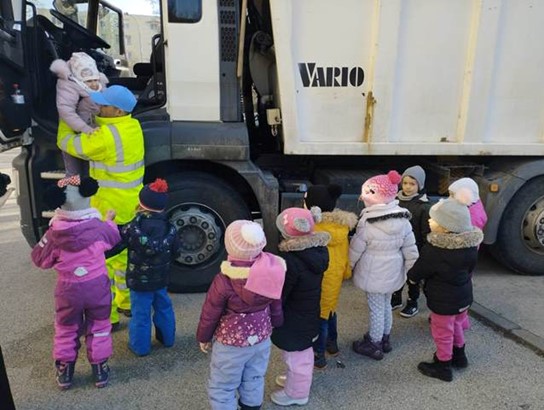 Társaságunk munkatársai segítik a gyerekeket a kukásautó vezetőfülkéjébe